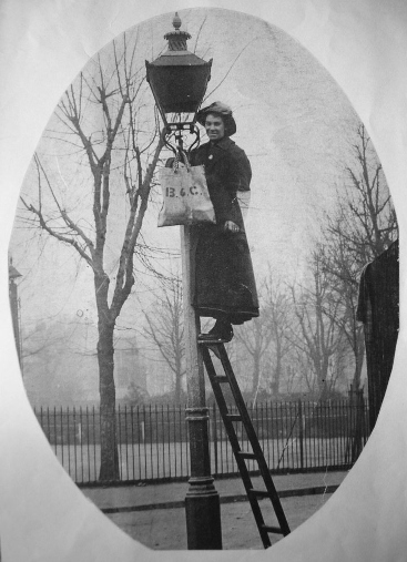 The same lady standing atop the ladder which is propped up against a gas light
